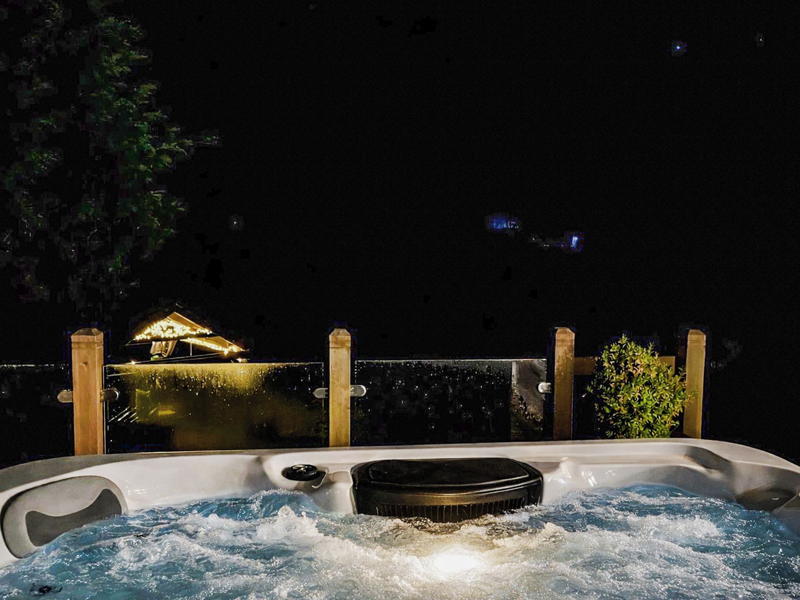 Un bain à remous avec vue sur un bâtiment illuminé la nuit.