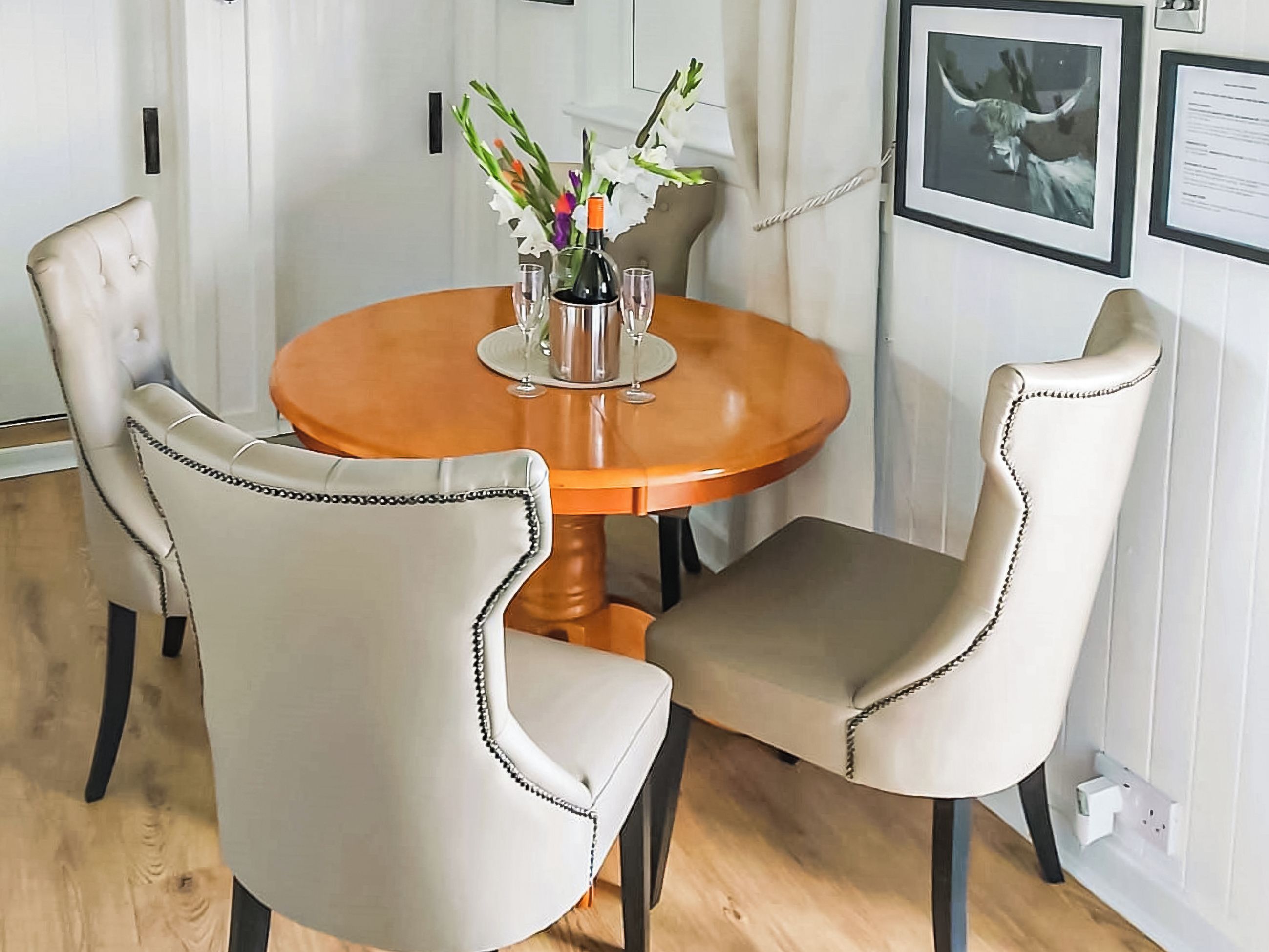 Une table à manger avec quatre chaises, un vase rempli de fleurs et des tableaux encadrés accrochés au mur.