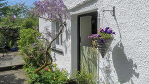A white cottage with a wooden door, a small window, and a hanging flower basket. - 1 bedroom accommodation in Bouth, Newby Bridge (Bouth, Newby Bridge)
