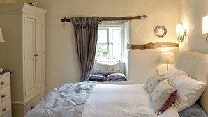 A bedroom with a bed, a nightstand, a dresser, a window with curtains, and a wall-mounted lamp. - 1 bedroom accommodation in Bouth, Newby Bridge (Bouth, Newby Bridge)