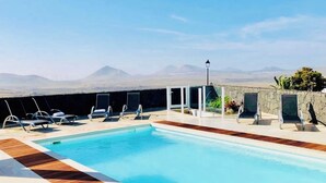 Área de piscina com espreguiçadeiras e vista para montanhas.