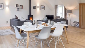 A modern living room with a fireplace, sofas, a dining table with chairs, and a television. - 3 bedroom accommodation in Balnaskeag, near Kenmore (Balnaskeag, near Kenmore)