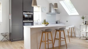 A modern kitchen with a central island, bar stools, a built-in oven, and a skylight. - 3 bedroom accommodation in Balnaskeag, near Kenmore (Balnaskeag, near Kenmore)