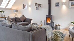A modern living room with a grey sofa, a standing lamp, a bookshelf, a fireplace, and a skylight. - 3 bedroom accommodation in Balnaskeag, near Kenmore (Balnaskeag, near Kenmore)
