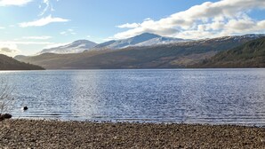 A lake with mountains in the background and a pebbly shore. - 3 bedroom accommodation in Balnaskeag, near Kenmore (Balnaskeag, near Kenmore)
