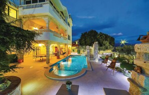 A multi-story hotel with a swimming pool, outdoor seating, and a stone fountain.