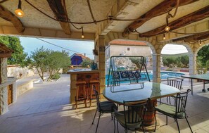 Un espace extérieur aménagé avec des sièges, une piscine, des murs en pierre et un plafond en bois rustique.