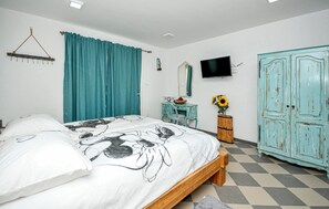 Une chambre à coucher comprenant un lit, une commode, une coiffeuse, un téléviseur et une armoire.