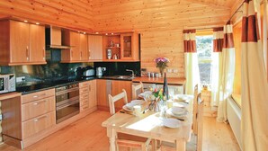 Une cuisine rustique aménagée dans une cabane en bois, avec un coin repas, comprenant une cuisinière, un four, un four à micro-ondes et une table à manger pour quatre personnes.