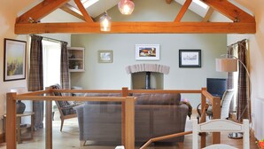 A cozy living room with a sofa, a fireplace, and a television. - 2 bedroom accommodation in Ravenstonedale, near Kirkby Stephen (Ravenstonedale, near Kirkby Stephen)