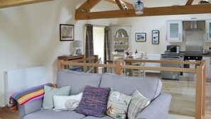 A living room with a grey sofa, colorful blanket, and various pillows. A wooden dining table and chairs are in the background. - 2 bedroom accommodation in Ravenstonedale, near Kirkby Stephen (Ravenstonedale, near Kirkby Stephen)