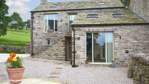 A stone house with a gravel driveway and a flower pot. - 2 bedroom accommodation in Ravenstonedale, near Kirkby Stephen (Ravenstonedale, near Kirkby Stephen)