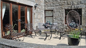 A stone building with a patio area featuring wooden benches, a table, and a hanging chair. - 1 bedroom accommodation in Dalbeattie, near Dumfries (Dalbeattie, near Dumfries)