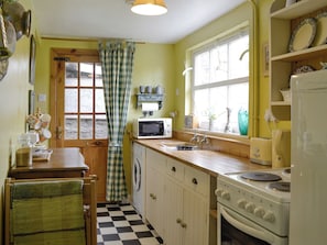 A compact kitchen with a washing machine, a microwave, and a stove.