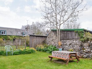 A rustic outdoor setting with a wooden table, a bench, and a stone wall.