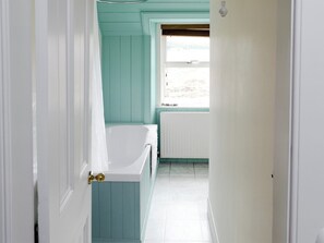 A narrow hallway with a bathtub, a window, and a radiator. - 3 bedroom accommodation in Rosehall, near Lairg (Rosehall, near Lairg)