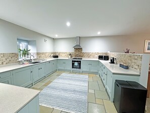 A modern kitchen with light blue cabinets, a central island, a built-in oven, a microwave, and a black refrigerator. - 3 bedroom accommodation in Tantobie, Stanley (Tantobie, Stanley)
