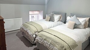 A bedroom with two beds, a radiator, a window with a blind, and a chandelier. - 3 bedroom accommodation in Tantobie, Stanley (Tantobie, Stanley)