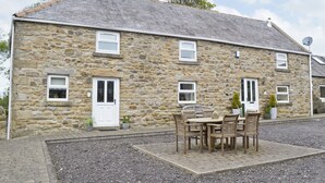 A stone building with a tiled roof, a front door, and a small patio with a table and chairs. - 3 bedroom accommodation in Tantobie, Stanley (Tantobie, Stanley)