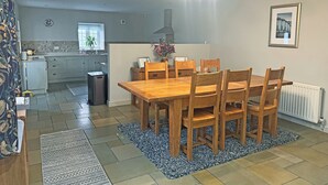 A dining area with a wooden table and chairs, a kitchen in the background, and a ceiling light fixture. - 3 bedroom accommodation in Tantobie, Stanley (Tantobie, Stanley)