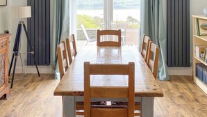 Et spiseområde med et træbord, stole, en tripodlampe og en bogreol.