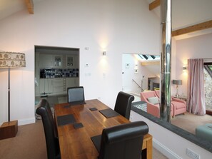 A dining area with a wooden table and chairs, a kitchen in the background, and a staircase leading to an upper level. - 2 bedroom accommodation in Inverlussa, near Achnamara (Inverlussa, near Achnamara)