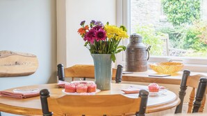 Een ronde houten tafel met een bloevas, een metalen pot en een gele kom.