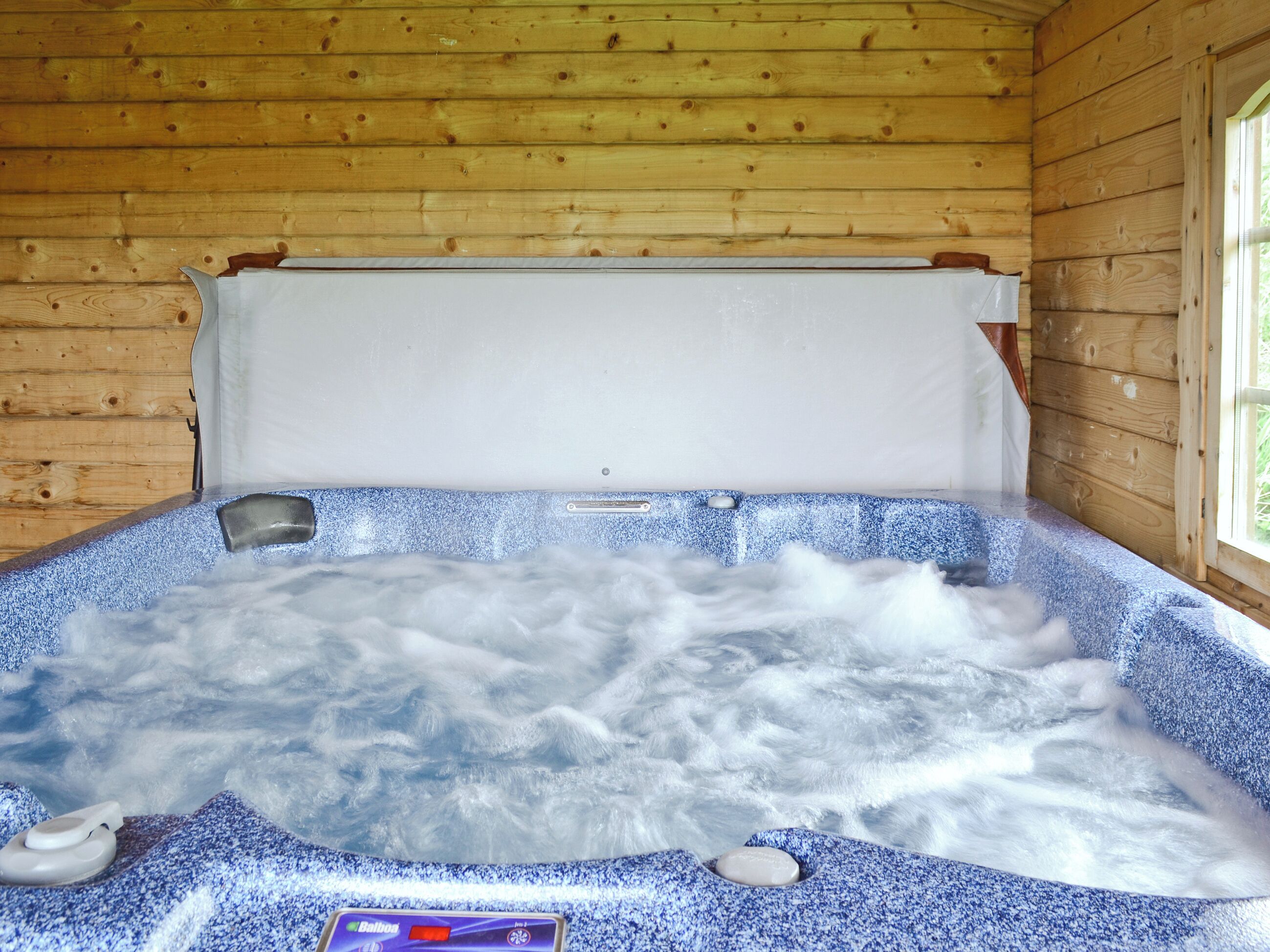 Una cabaña de madera con un jacuzzi.