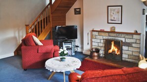 Un salon avec une cheminée, un téléviseur, un escalier et un canapé rouge.