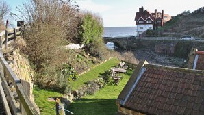 Une vue sur la côte, avec un pont en pierre, des zones herbeuses et un bâtiment doté d’un toit rouge.