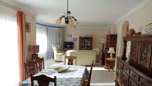 A dining area with a table set for four, a television, and a cabinet with decorative items. - PENVENAN 22710. House 4 PERSONS. Close to shops. 3km from beaches (Penvénan)
