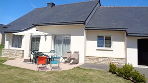 A house with a dark roof, a patio with outdoor furniture, and a stone foundation. - PENVENAN 22710. House 4 PERSONS. Close to shops. 3km from beaches (Penvénan)