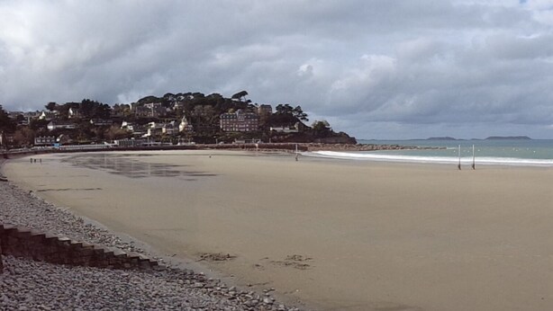 A wide, empty beach with a rocky shoreline and buildings in the background. - PENVENAN 22710. House 4 PERSONS. Close to shops. 3km from beaches (Penvénan)