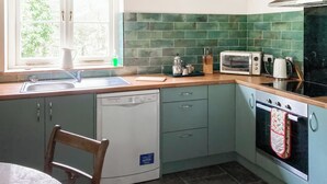 A kitchen with a dishwasher, a microwave, a kettle, and a toaster.