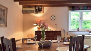 A dining table set with plates, glasses, and a vase of flowers.