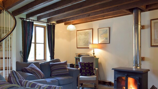 A cozy living room with a fireplace, a sofa set, a chair, and a lamp.