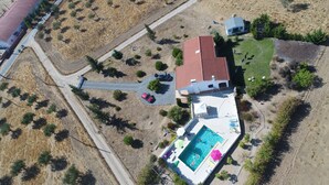 Vue aérienne d’une maison avec une piscine, un garage à toit rouge et une allée pavée.