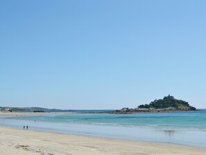 A beach with a small hill, clear sky, and calm water. - 2 bedroom accommodation in Near Marazion (Near Marazion)