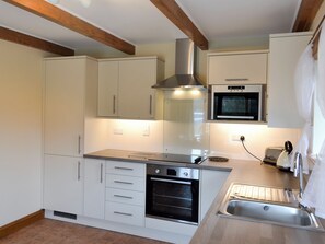 A modern kitchen with white cabinets, a stainless steel range hood, an oven, a microwave, and a sink.
