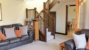 A living room with a leather sofa, a wooden bookshelf, and a staircase. - 2 bedroom accommodation in Apse Wood, near Shanklin (Apse Wood, near Shanklin)