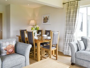 A dining area with a wooden table, chairs, a vase with flowers, and a painting on the wall. - 3 bedroom accommodation in Linlithgow, near Edinburgh (Linlithgow, near Edinburgh)