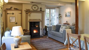 A cozy living room with a fireplace, a sofa, a table, and a chair. - 3 bedroom accommodation in Polruan-by-Fowey (Polruan-by-Fowey)