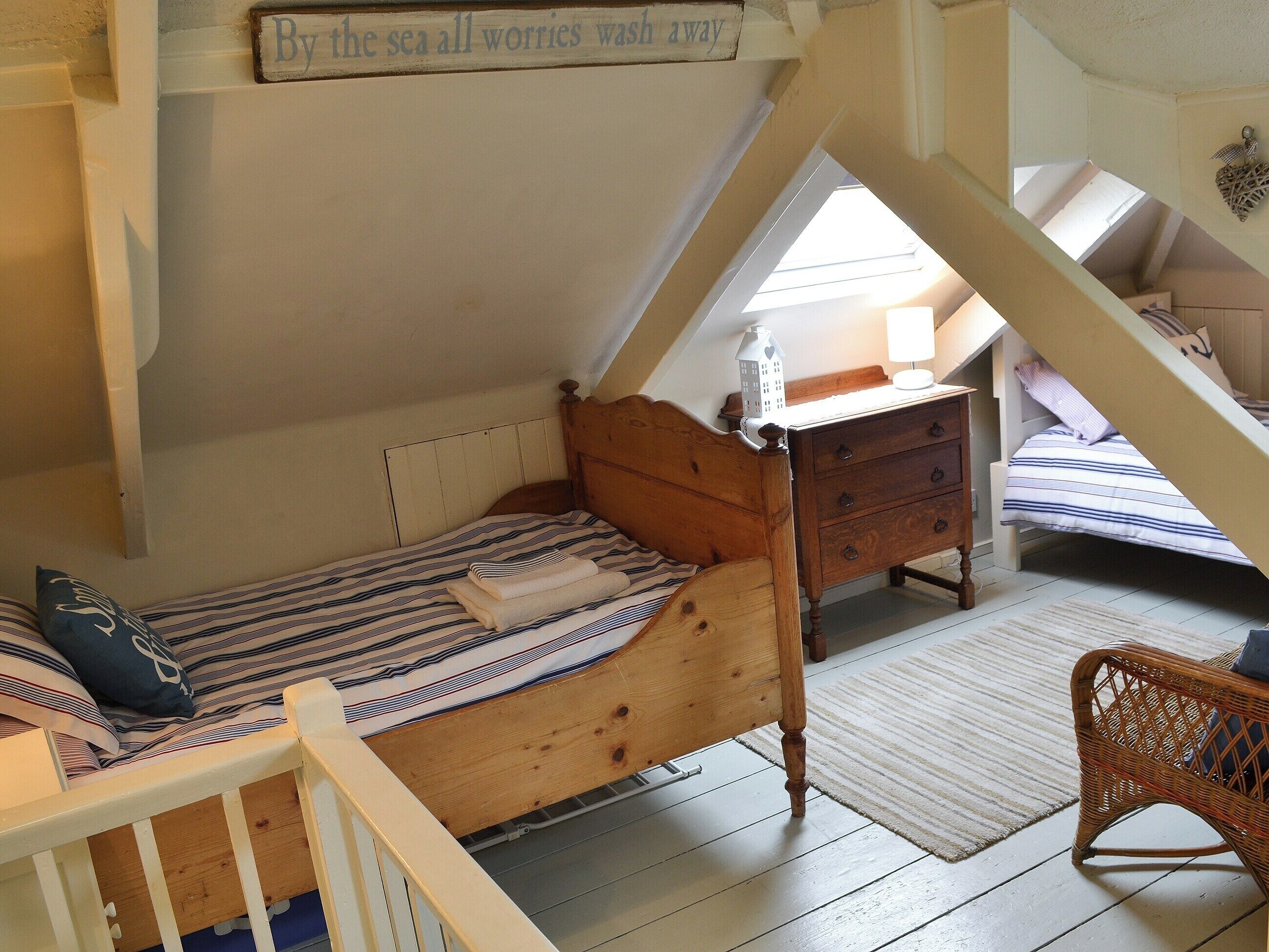 A cozy attic bedroom with a wooden bed, a nightstand, and a wicker chair.