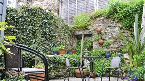A patio with a stone floor, surrounded by potted plants and a stone wall. - 3 bedroom accommodation in Polruan-by-Fowey (Polruan-by-Fowey)