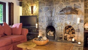 Un salon chaleureux avec une cheminée en pierre, un téléviseur et un canapé rouge.