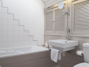 A bathroom with a bathtub, a sink, and a toilet. There is a towel hanging on the wall.