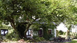 Une maison avec un banc en pierre et une table de pique-nique dans la cour.
