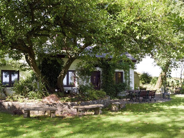 A house with a stone bench and a picnic table in the yard.