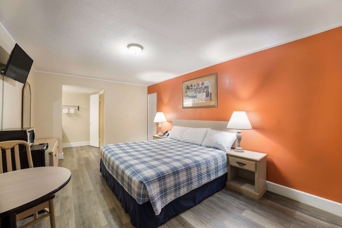 A hotel room with a bed, bedside tables, a desk, and a chair.