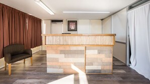 Un espace d’accueil comprenant un comptoir de réception en bois, un banc rembourré et un tableau encadré au mur.